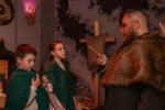 Mistrz gry w stroju wikinga tłumaczy zasady dwójce uczestników podczas wyjścia klasowego.
