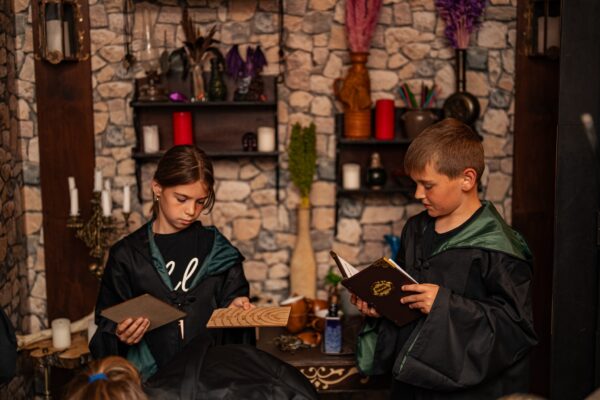 Dzieci w escape roomie rozwiązują zagadkę z magiczną księgą.