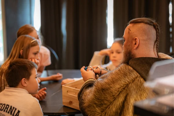 Dzieci podczas wyjścia klasowego słuchają opowieści wikinga.