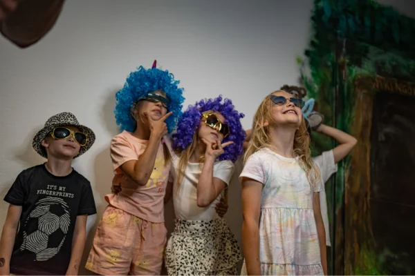 Urodziny dla dzieci w warszawskim escape room. Grupa dzieci fotografująca się przy fotobudce.