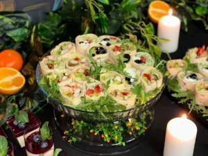 Roladki z tortilli z warzywami, sałatą i oliwkami, podane na paterze z rukolą – przekąska z menu Premium.