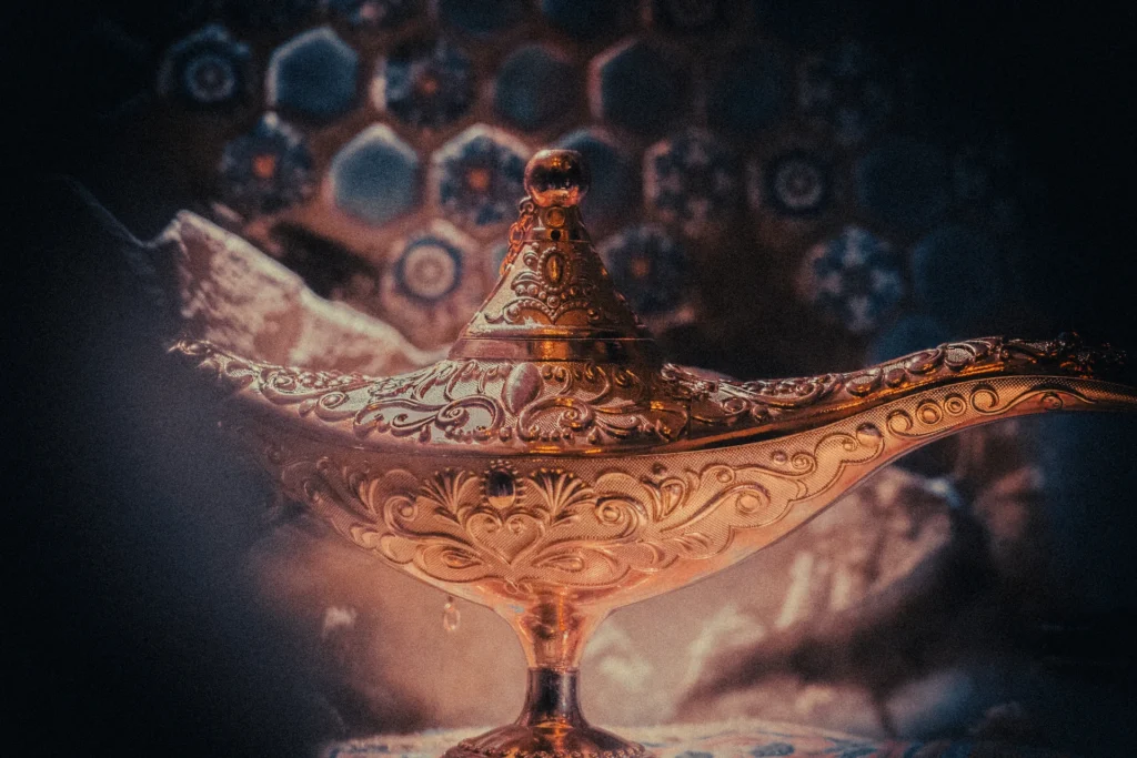 Zdobiona złota lampa w stylu orientalnym stojąca na tle niebieskich kafli.